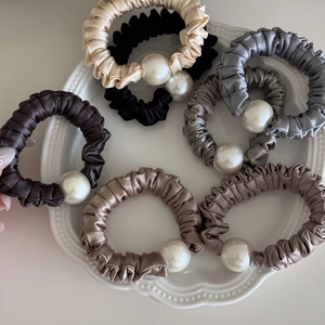 Elegant satin scrunchie set with white pearls in assorted Morandi colors on a ceramic tray