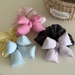 Detailed macro view of padded fabric 3D bow scrunchies in various pastel color tones