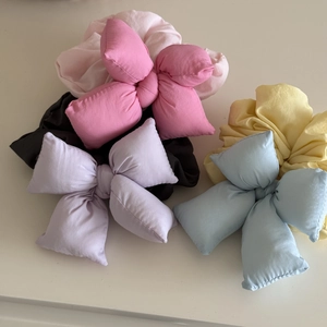 Detailed view of plush 3D puffy bow scrunchies in pastel macaron colors on a white base