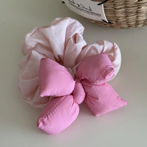 Detail of a padded 3D bow scrunchie showing pink fabric texture and stitching