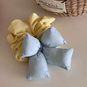 Detailed shot of yellow scrunchie featuring a soft light blue padded 3D bow hair tie