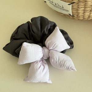 Detailed view of dark grey scrunchie featuring a soft lilac padded bow hair accessory