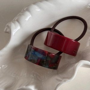 Detail view of burgundy and marble patterned acetate hair ties on a shell tray