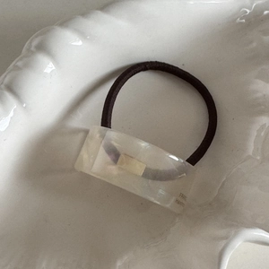 Close-up of translucent acetate hair tie featuring a France Handmade engraved metal buckle