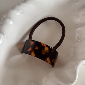 Close-up of tortoise shell pattern hair tie with France Hand Made text on a white shell tray