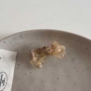 Detail of a mini acetate amber bow hair claw with hollow patterns on a ceramic tray