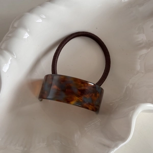 Detail of tortoiseshell acetate hair tie with France Handmade text in a shell bowl