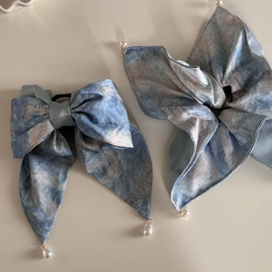 Détail d'un ensemble de pinces à cheveux en satin bleu avec motif de peinture à l'huile