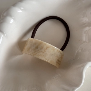 Close-up of geometric marble resin hair tie with France Handmade text in a shell dish