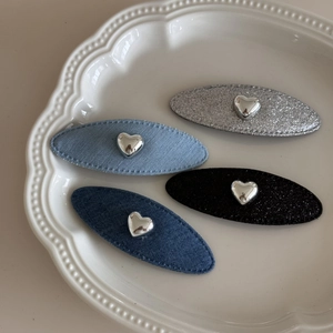 Dettaglio di fermagli per capelli a cuore in denim e glitter in un piatto di ceramica