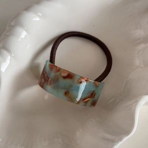 Macro shot of marble acetate ring and high-elastic hair tie on white shell tray