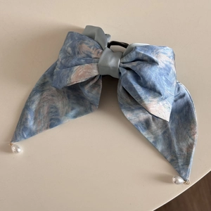 Détail de la pince à cheveux style Monet avec pendentifs en perles et texture satinée élégante