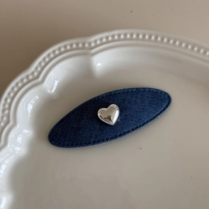 Vista dettagliata di un fermaglio ovale in denim con ciondolo a cuore in metallo argento