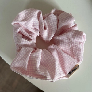 Detailed view of large pink gingham hair scrunchie with brand logo tag on white background