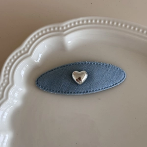 Dettaglio molletta ovale in denim con cuore d'argento su un piatto di ceramica