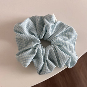 Macro detail of large light blue gingham checkered scrunchie with soft fabric pleats