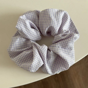 Close-up of a large purple and white gingham checkered scrunchie in cotton fabric