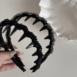 Détail d'un serre-tête noir ondulé avec perles de cristal et pointes de style gothique