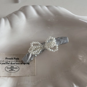 Dettaglio di un fermaglio per capelli argento glitterato con perle su piatto a conchiglia