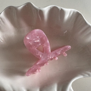 Détail d'une pince à cheveux en acétate rose avec texture marbrée dans un coquillage