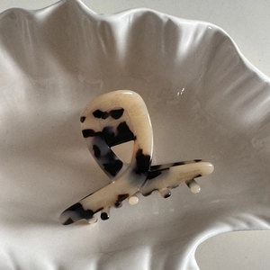 Détail de la pince à cheveux en acétate avec motif tortue dans un plat coquillage