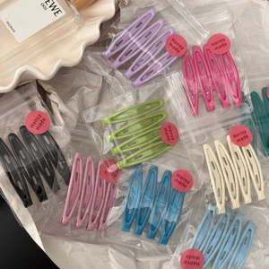 Detail of colorful teardrop BB hair clips set arranged on a white textured background