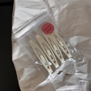 Detailed view of 4-pack cream-colored metal snap hair clips in transparent poly bag