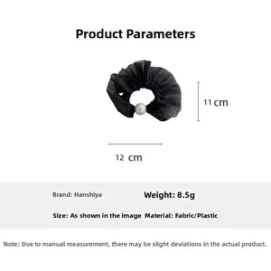 Close-up of black mesh scrunchie featuring a large white pearl center and elastic fabric