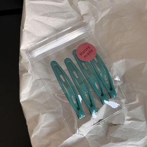 Set of four dark green metal snap hair clips neatly packed in a clear zipper bag