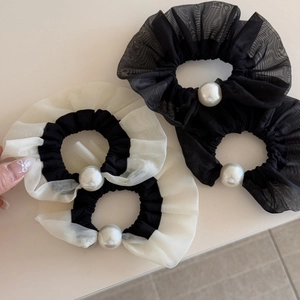 Close-up of elegant organza lace hair scrunchies with large pearl details in black and cream