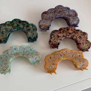 Detail view of marble acetate hair claws with vintage patterns and colorful rhinestones