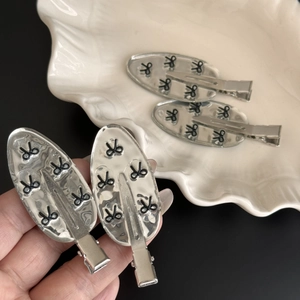 Set of 4 silver metallic bow hair clips with Y2K aesthetic on a ceramic tray