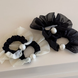 Detail of three mesh hair scrunchies with elegant pearls on a soft white background