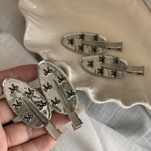 Detail of four silver oval hair clips with black butterfly pattern and hammered texture