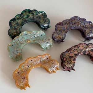 Detail of five large marble acetate hair claws with elegant gold and silver filigree patterns