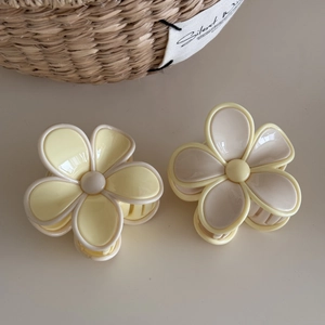 Detail shot of pastel floral hair claws in soft yellow and beige matte resin finish