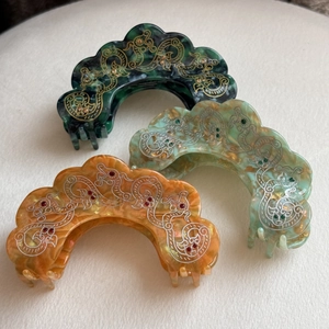 Detailed macro of vintage marble textured hair claw clips with elegant cloud patterns