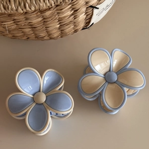Close-up of dual-tone flower hair claws in blue and cream resin for hair styling