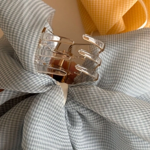 Detail of light blue plaid bow hair claw clip with transparent base and metal spring