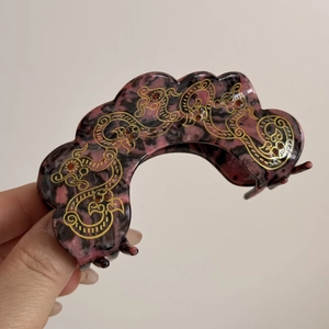 Detail of vintage acetate hair claw with marble texture and golden dragon pattern