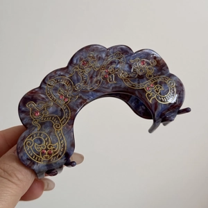 Macro detail of vintage purple acetate hair claw clip with golden dragon etchings and rhinestones