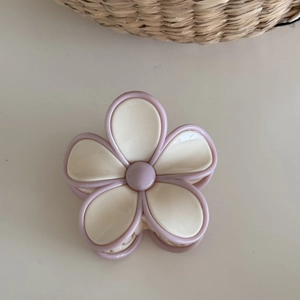 Detail of flower hair claw clip with cream petals and soft purple accents for hairstyling