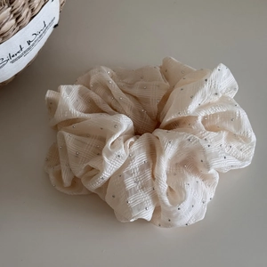 Detail of cream oversized scrunchie with silver studs and subtle checkered texture