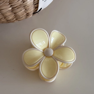 Detailed view of yellow and cream floral hair claw clip on minimalist background