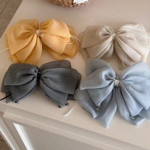 Macro detail of plaid tulle bow hair clips in yellow, beige, grey, and blue colors