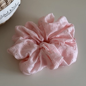 Detail of pink seersucker fabric scrunchie with silver rhinestones and textured finish