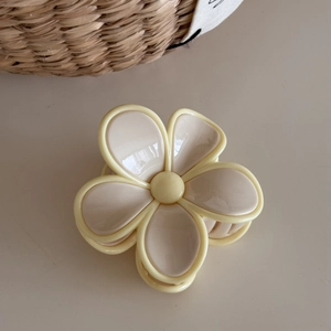 Macro detail of the cream-beige flower hair claw clip with a glossy resin finish