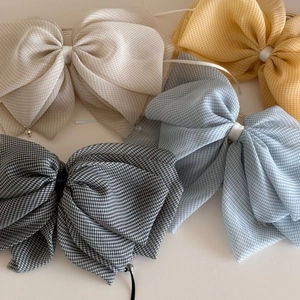Detail showing sheer plaid bow hair clips in beige, yellow, blue and grey colors
