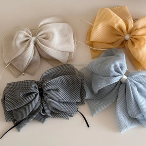 Detailed view of four large gingham bow hair clips with delicate crystal bead accents