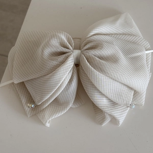 Detail view of multi-layered plaid bow hair claw with iridescent crystal pendant